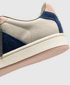 Close-up of men's streetwear sneaker in beige, navy blue suede, and blush accents