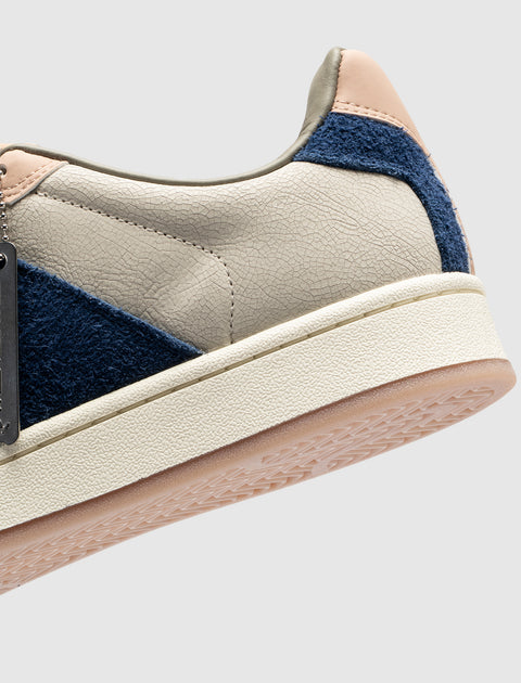 Close-up of men's streetwear sneaker in beige, navy blue suede, and blush accents