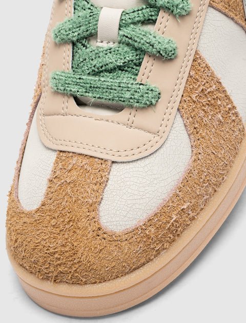 Close-up of brown suede and white leather sneaker with green laces, streetwear style