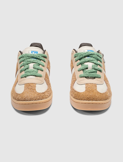 Pair of brown and white fuzzy sneakers with green laces on a white background