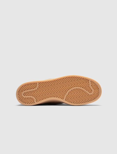 Brown gum rubber sneaker outsole with herringbone traction pattern on white background