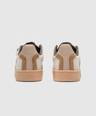 Rear view of brown and white low-top sneakers with gum soles on white background.