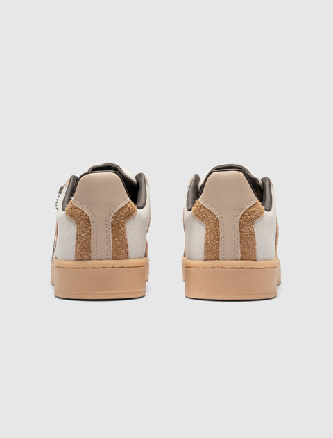 Rear view of brown and white low-top sneakers with gum soles on white background.