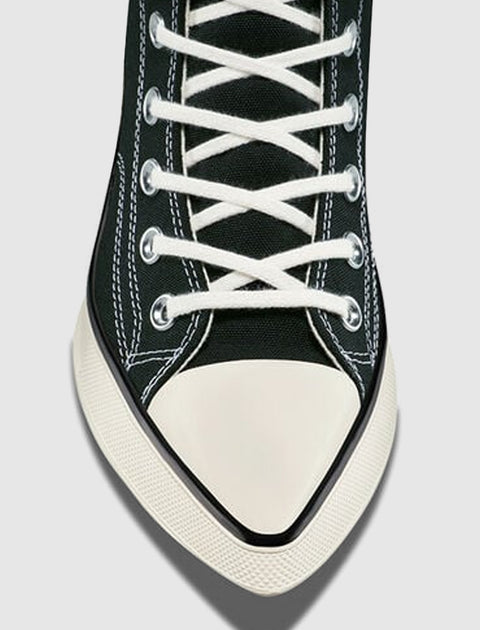 Black canvas sneaker with white laces, white rubber toe cap, and visible stitching