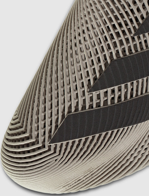 Close-up of beige sneaker toe with geometric mesh pattern and black stripes