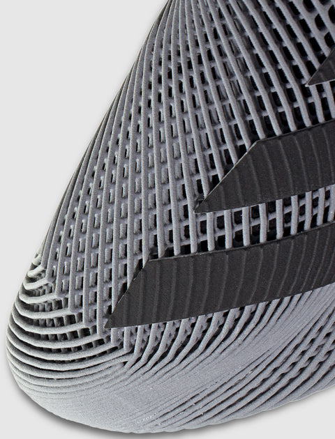 Close-up of a grey sneaker toe with textured mesh and black stripe accents