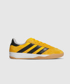 Yellow and black suede low-top sneaker with gum sole on white background