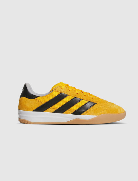 Yellow and black suede low-top sneaker with gum sole on white background