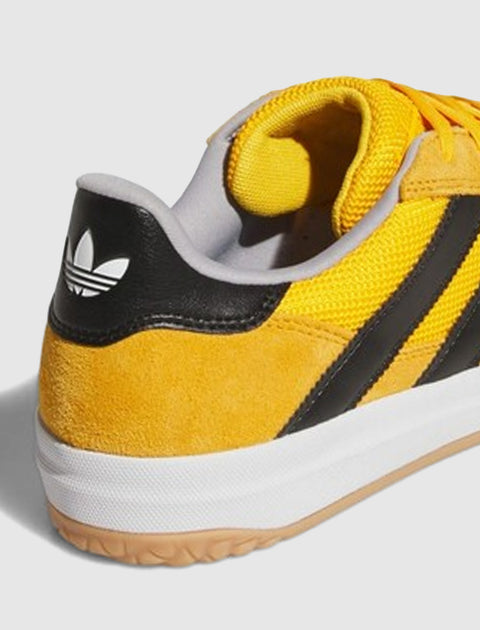 Yellow and black suede sneaker with gum sole and white logo on the heel