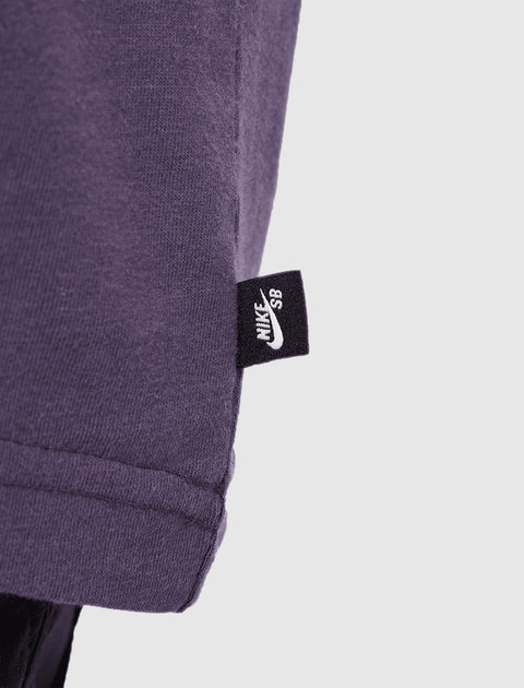 Close-up of purple t-shirt hem with black Nike SB tag, streetwear apparel detail