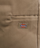 Close-up of khaki pants with a pocket and visible Dickies logo patch, streetwear style.