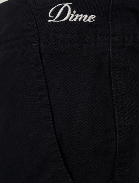 Close-up of black pants pocket with white Dime logo embroidery, men's streetwear fashion.