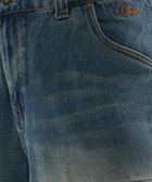 Close-up of blue denim jeans with orange stitching and embroidered Dime logo on pocket