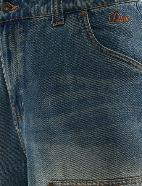 Close-up of blue denim jeans with orange stitching and embroidered Dime logo on pocket