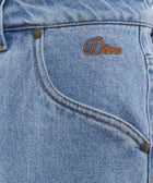 Close-up of light blue denim jeans with orange Dime embroidery and front pocket