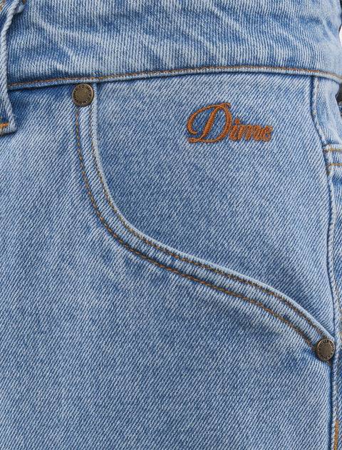 Close-up of light blue denim jeans with orange Dime embroidery and front pocket
