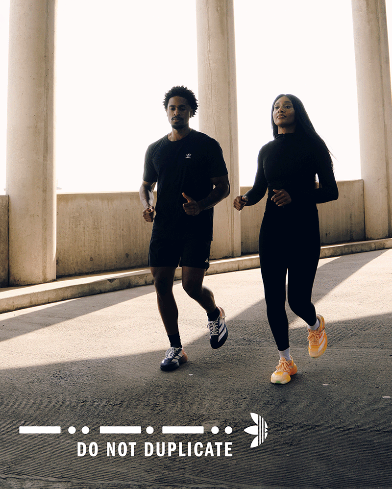 Two people jogging outdoors in stylish black activewear and sneakers, urban setting