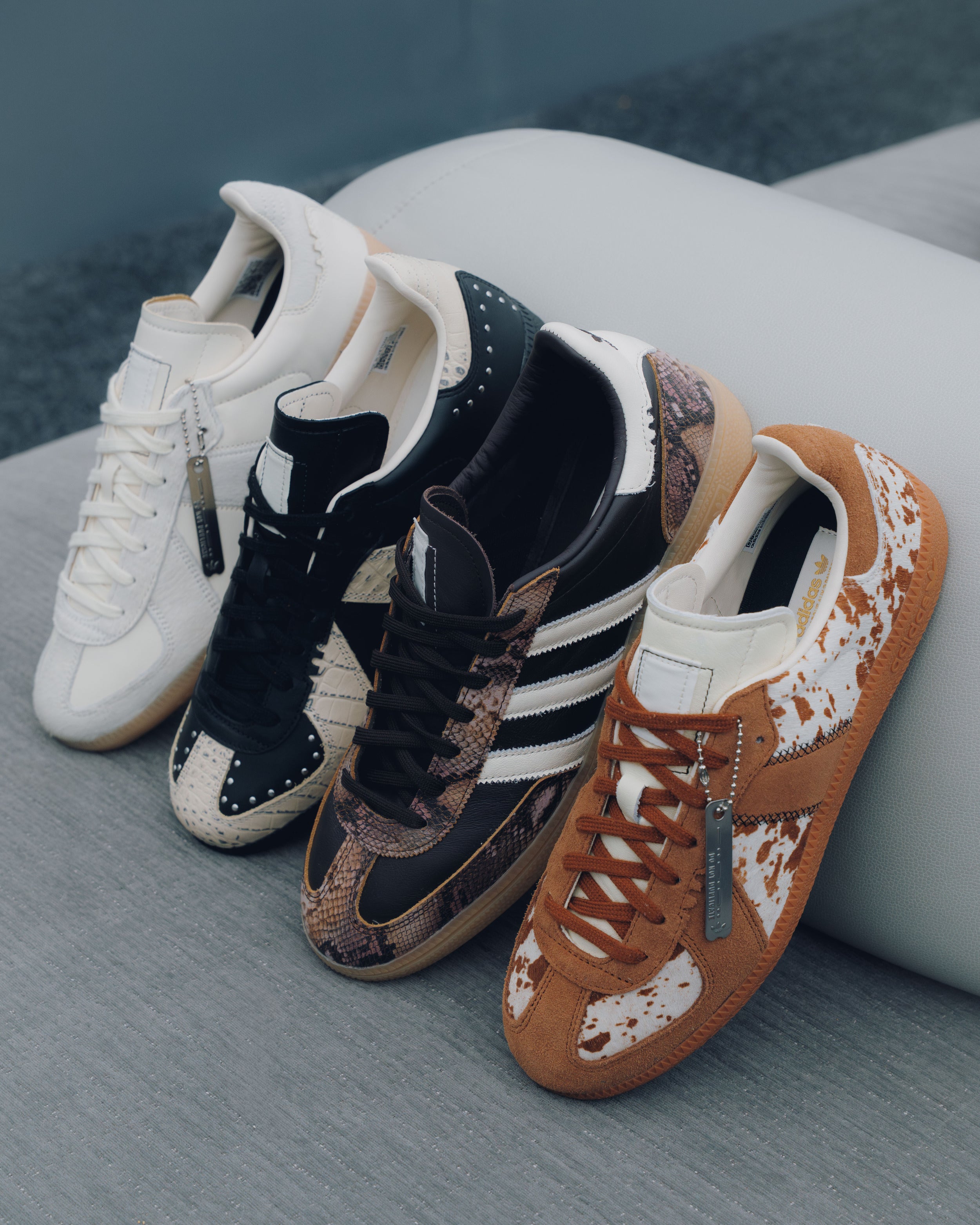 Four pairs of men's streetwear sneakers in neutral tones and animal prints on a modern sofa.