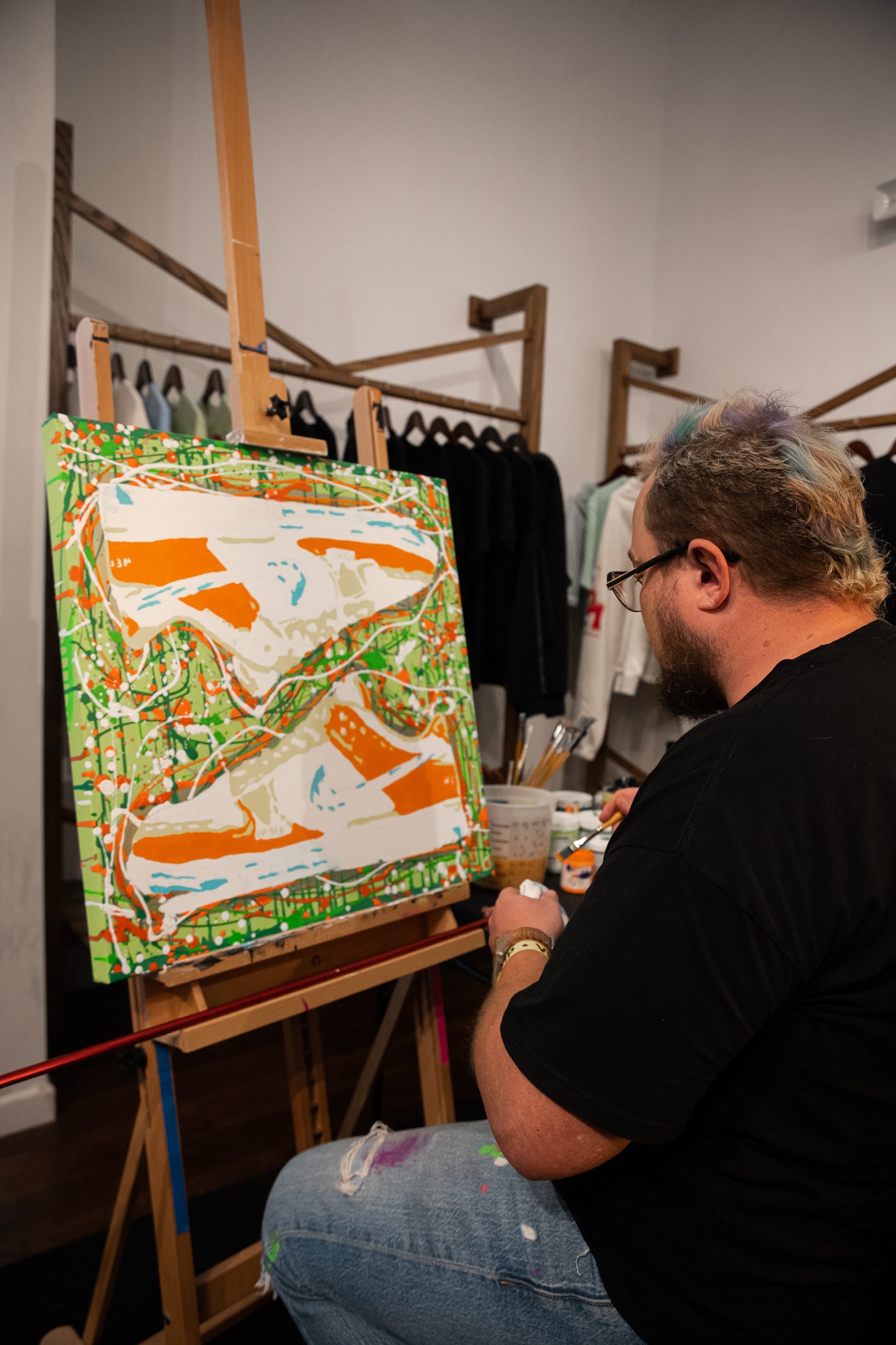 Man painting abstract sneakers artwork on canvas in a streetwear clothing store