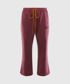Burgundy velour track pants with yellow drawstring and embroidered script on left leg