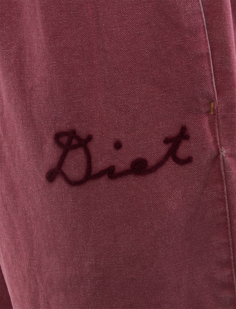 Close-up of maroon fabric with embroidered 'Diet' script, men's streetwear detail