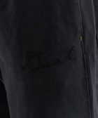 Close-up of black streetwear pants with subtle embroidered script on the leg