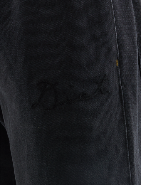 Close-up of black streetwear pants with subtle embroidered script on the leg