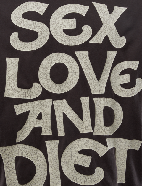 Cracked white text graphic on dark streetwear top with bold slogan design
