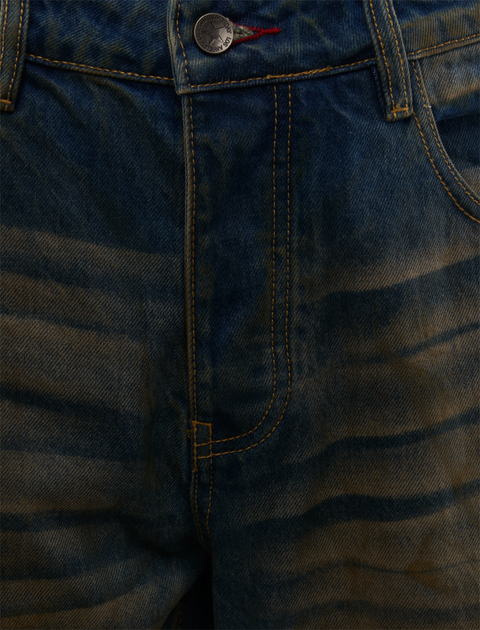Close-up of blue denim jeans with yellow stitching and wavy faded pattern