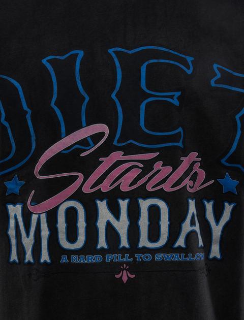 Close-up of black streetwear shirt with bold text Diet Starts Monday and stars graphic.