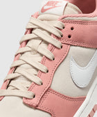 Closeup of Nike sneaker with pink suede overlays, cream laces, and white Swoosh logo