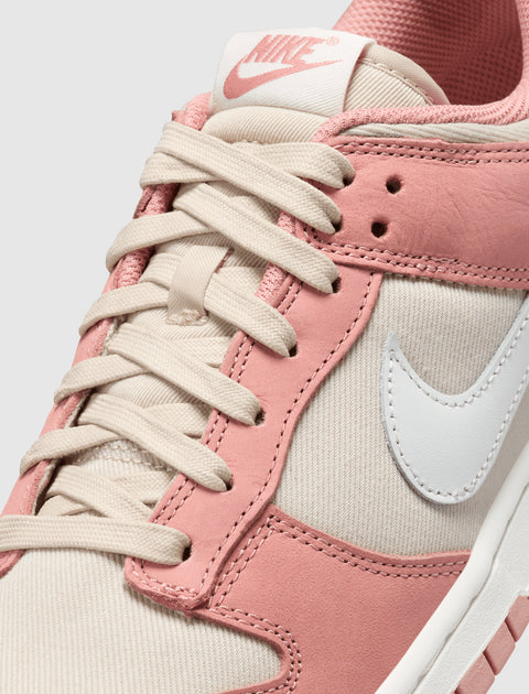 Closeup of Nike sneaker with pink suede overlays, cream laces, and white Swoosh logo