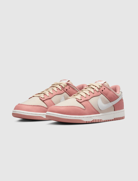 Low-top sneakers in pink and beige with a white swoosh logo, side view on white background