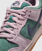 Close-up of Nike SB Dunk Low Pro sneaker in pink and green suede with blue Swoosh