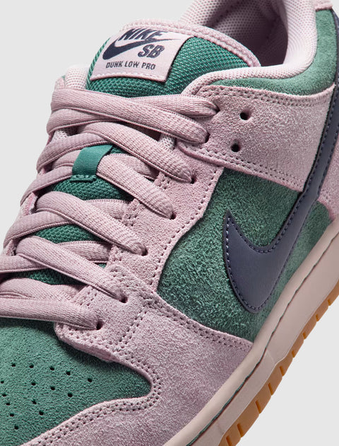 Close-up of Nike SB Dunk Low Pro sneaker in pink and green suede with blue Swoosh