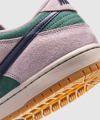 Close-up of suede sneaker in pink, green, and navy with gum outsole on white background