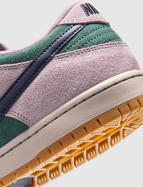 Close-up of suede sneaker in pink, green, and navy with gum outsole on white background