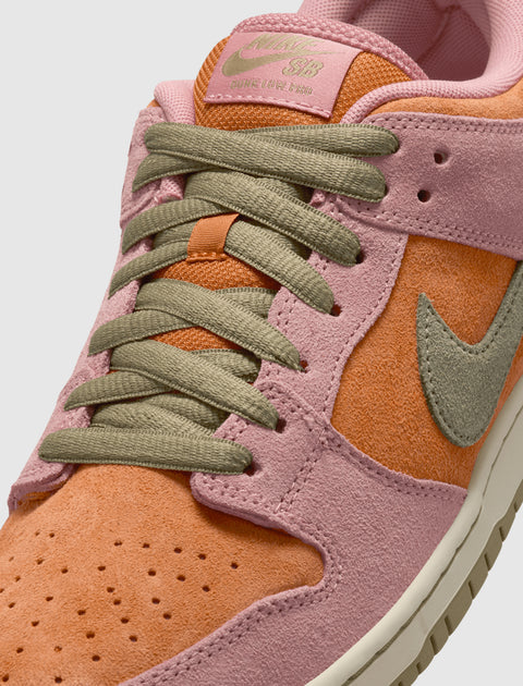 Close-up of suede sneaker with pink, orange, and olive green accents and laces