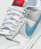 Close-up of white and grey sneaker with blue swoosh and red tongue label, white laces