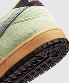 Closeup of sneaker heel with light green suede upper, gum midsole, and textured black outsole