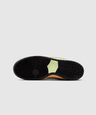 Close-up of black and green sneaker sole with circular tread pattern on gray background