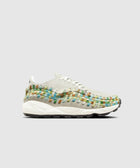 White sneaker with multicolor woven accents, side profile, on gray background