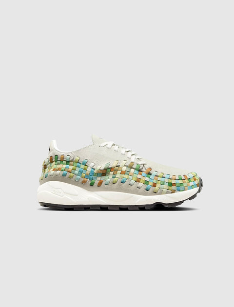 White sneaker with multicolor woven accents, side profile, on gray background