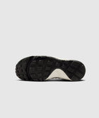 Closeup of sneaker outsole with black rubber tread and textured grip pattern on a white background.