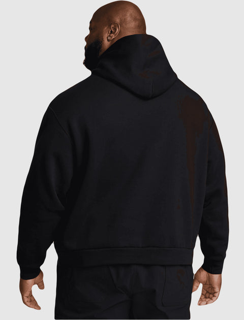 Man wearing a black hooded streetwear sweatshirt, back view, against a gray background.
