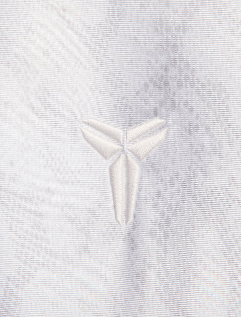 Close-up of white embroidered logo on textured white fabric, streetwear apparel detail