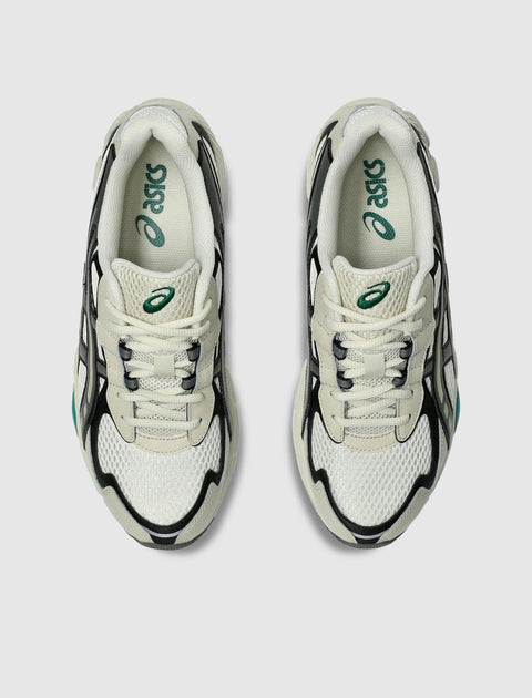 Top view of white and black mesh sneakers with green logo accents on insoles