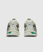 Rear view of beige mesh sneakers with black and green accents on a plain background