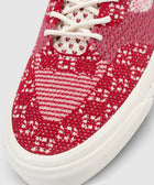 Red and white knit sneaker close-up with textured upper and white sole