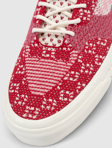 Red and white knit sneaker close-up with textured upper and white sole